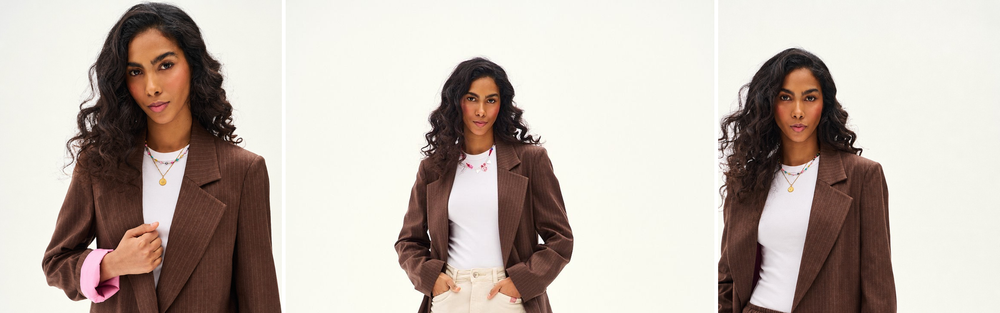 Woman in a brown pinstripe blazer with a white T-shirt and cream trousers, studio photograph