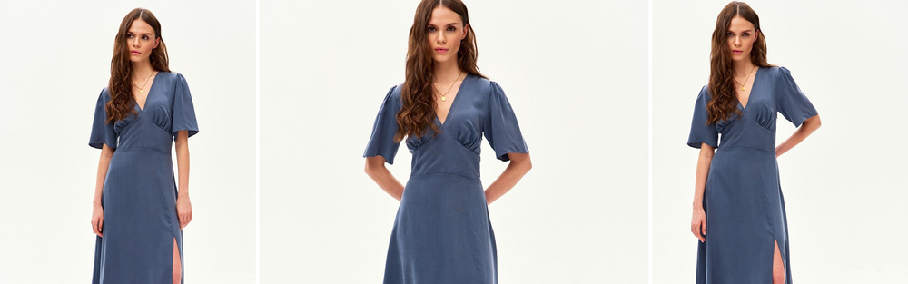 Woman in a cornflower blue midi dress with a V neckline, a blue shade with a violet note.