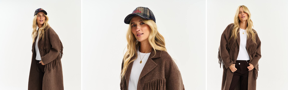 Woman in a long brown wool coat with fringe over a white T-shirt, studio photograph