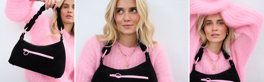 Woman in a pink sweater with a black suede shoulder bag.