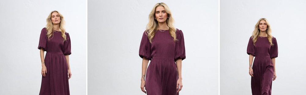 Woman in a purple midi dress with a puff sleeve, a shade on the border of red and violet.